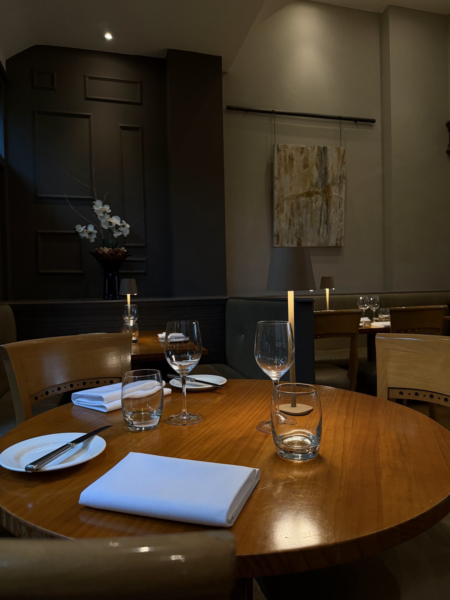 A laid table at Bradley's with a lit table lamp, orchids on the shelf behind