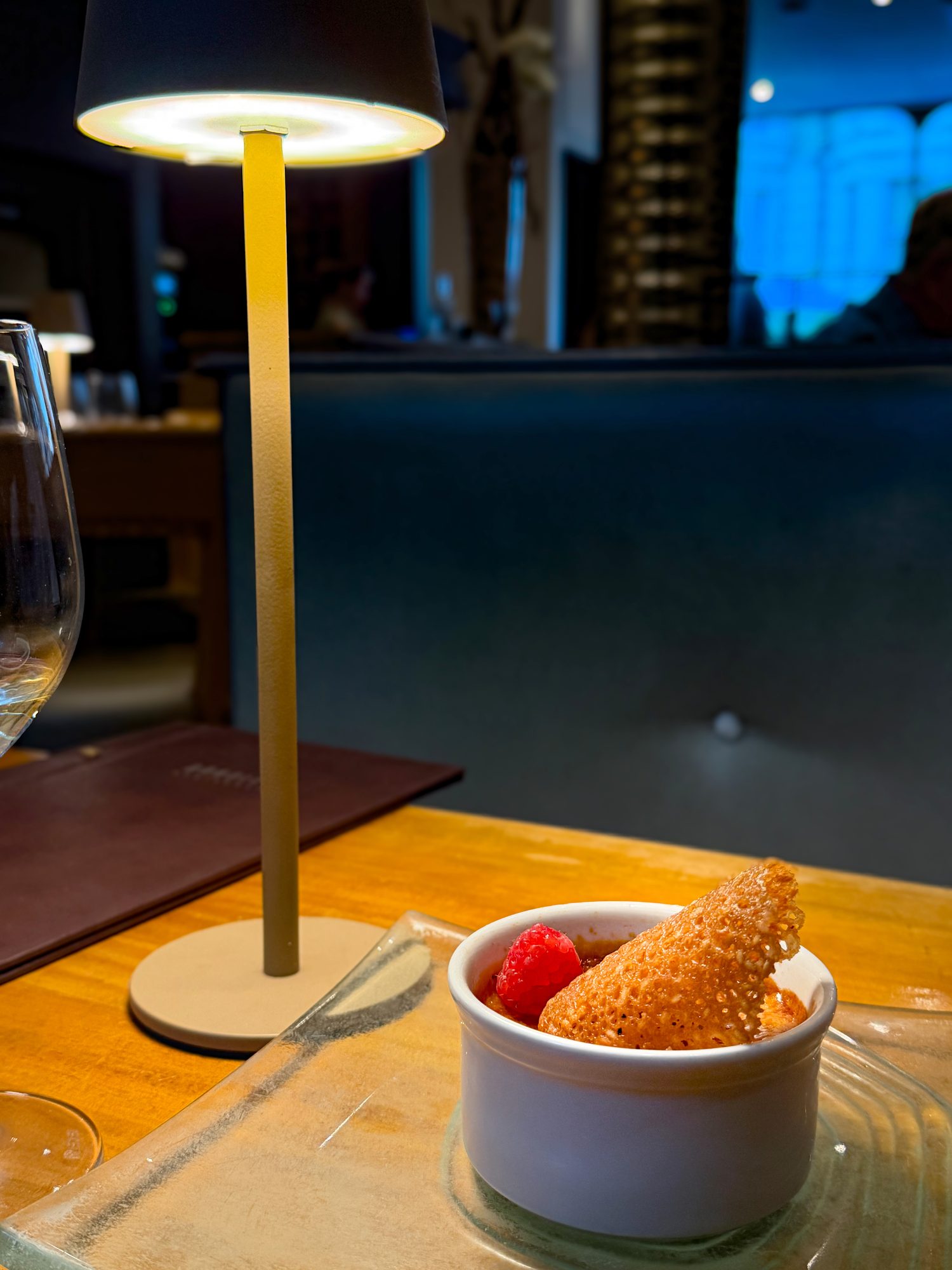 Raspberry crème brûlée with a sesame tuile, lit by the table lamp