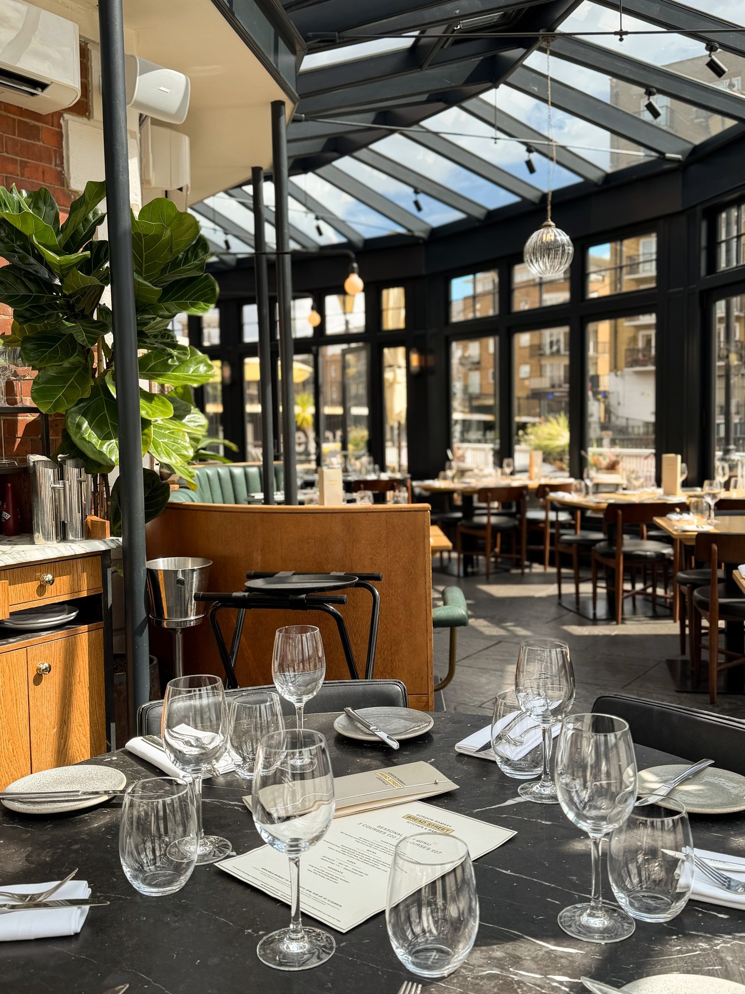 Wider view of the conservatory dining space with laid marble tables