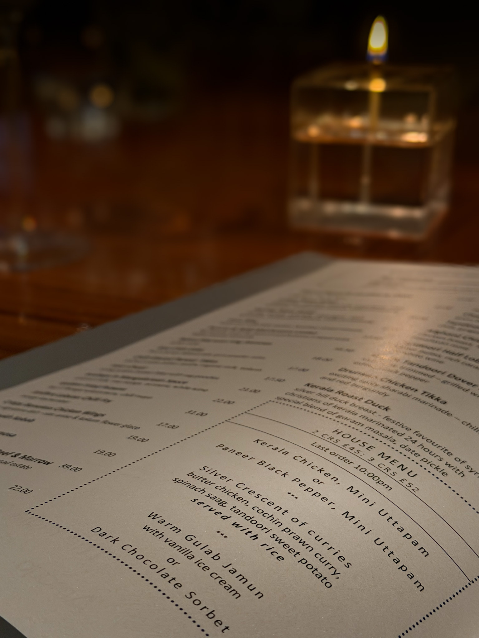 The printed House Menu at Chutney Mary on the table beside a lit candle