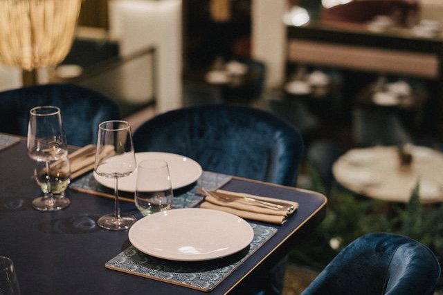 Blue velvet chairs around a table laid for dinner in the dining room at Kahani