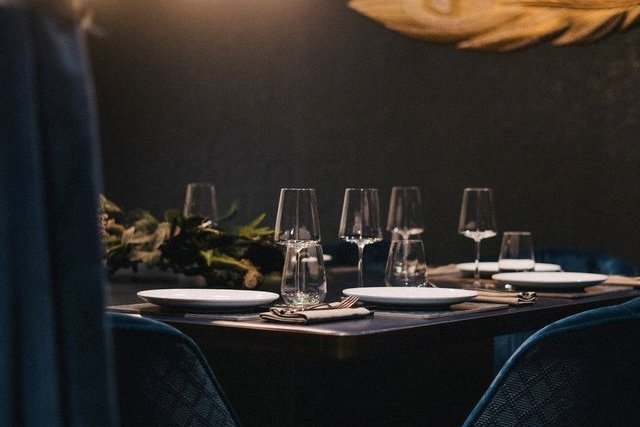 A table laid with glassware and white plates against a dark blue wall at Kahani