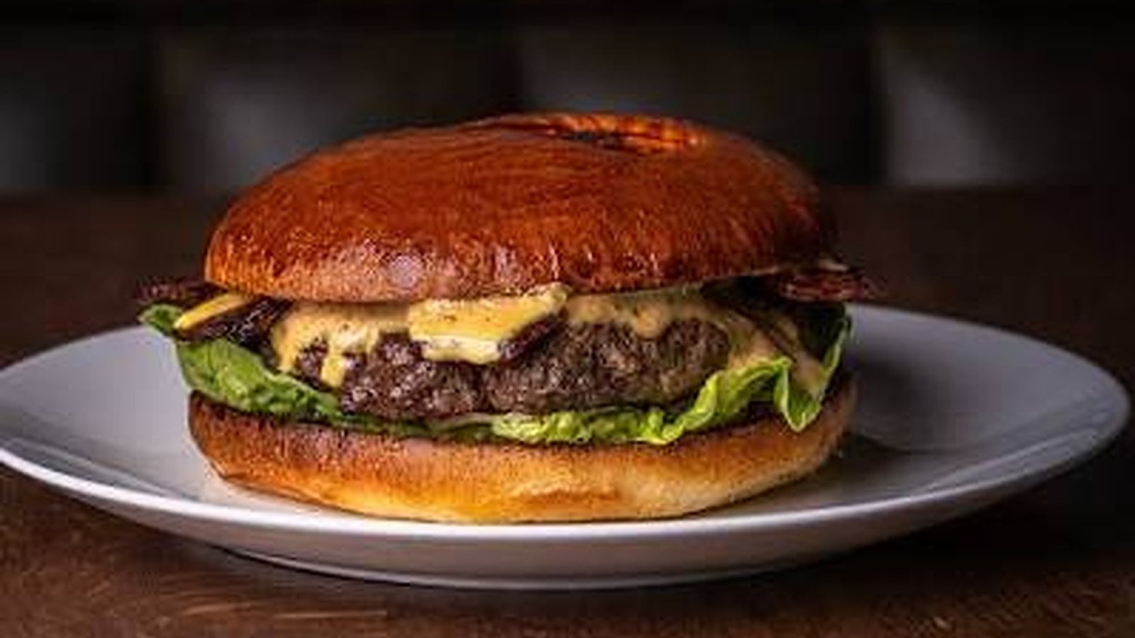 Fallow's dairy cow burger with cheese and lettuce on a white plate