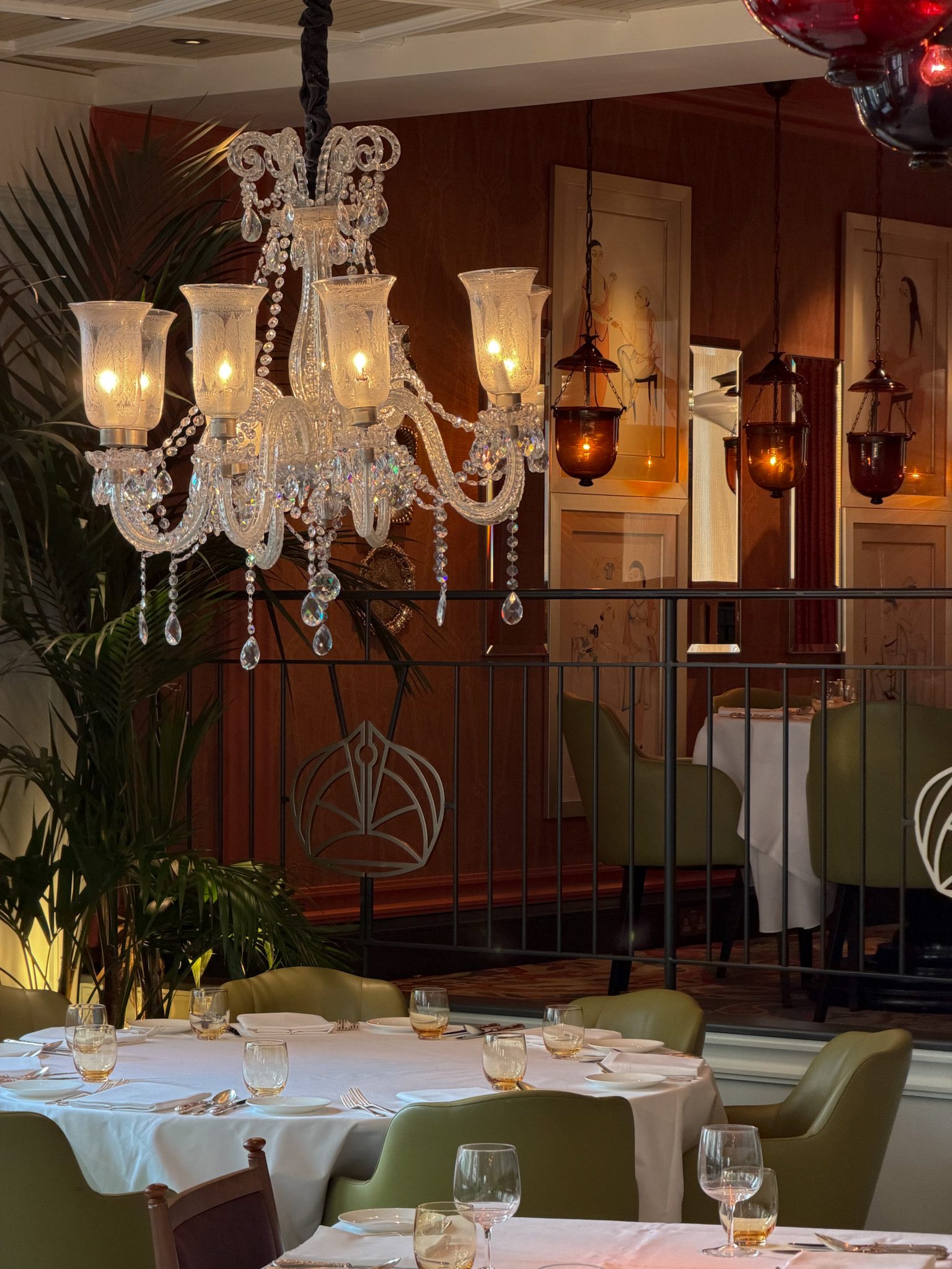 Close-up of the crystal chandelier above tables with green chairs
