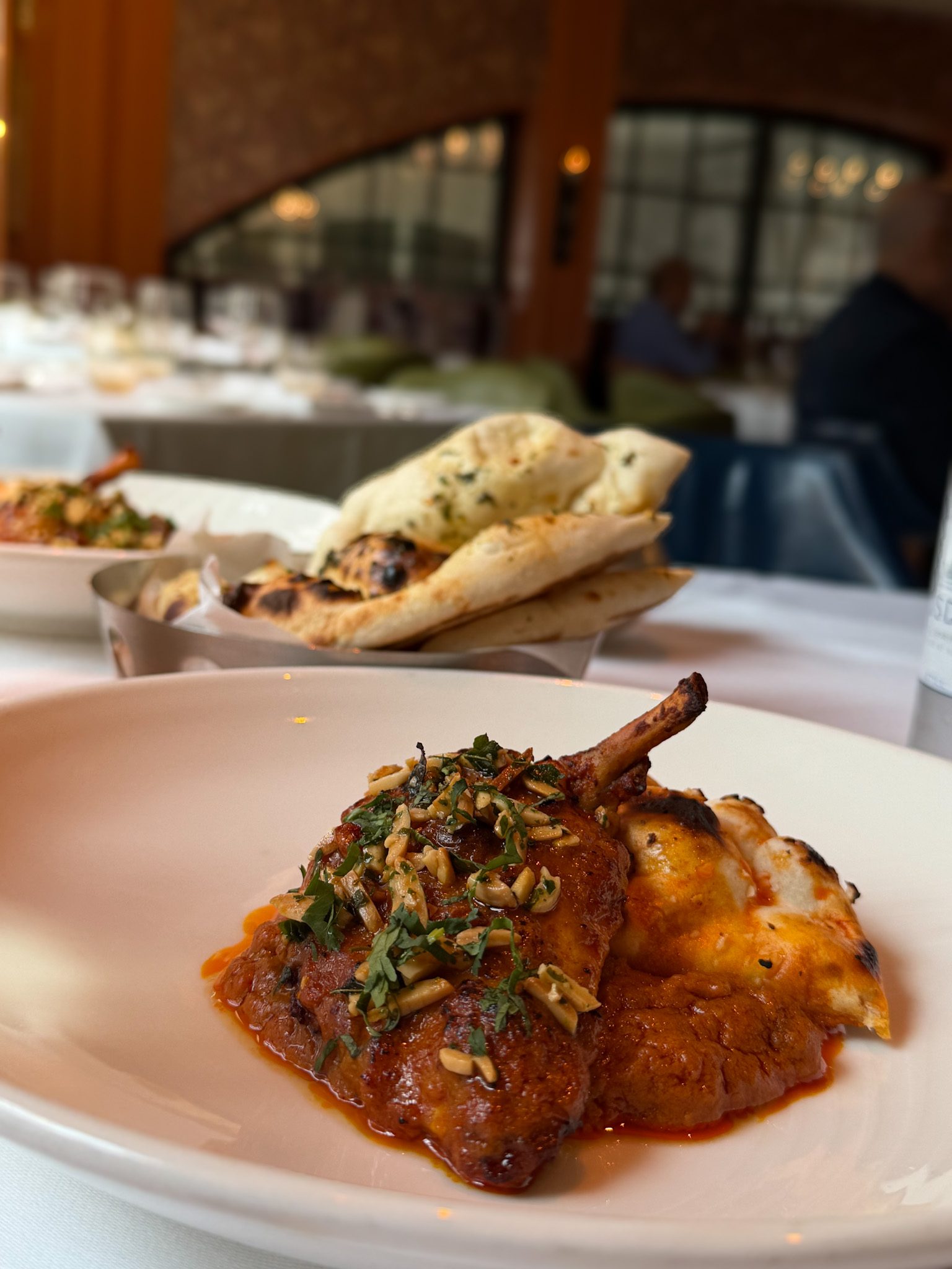 Country Captain chicken on the bone in a red sauce with slivered nuts and coriander, with roghni mini naans